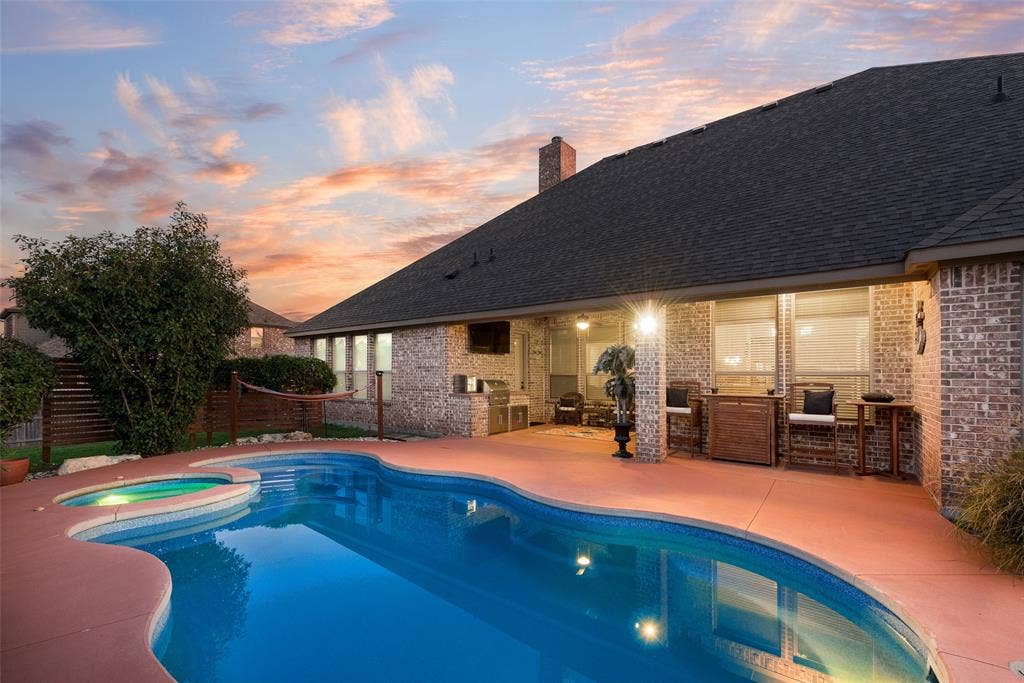7231 Judy Drive, Ovilla, TX 75154 Brick exterior, covered patio, and in-ground swimming pool with an attached spa, complemented by an outdoor kitchen station