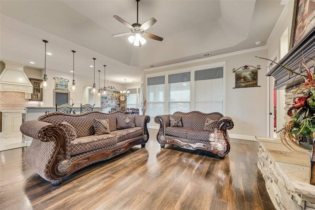7231 Judy Drive, Ovilla, TX 75154 Tray ceiling with integrated fan, wood-finish flooring, stone-surround fireplace with mantel, and recessed lighting