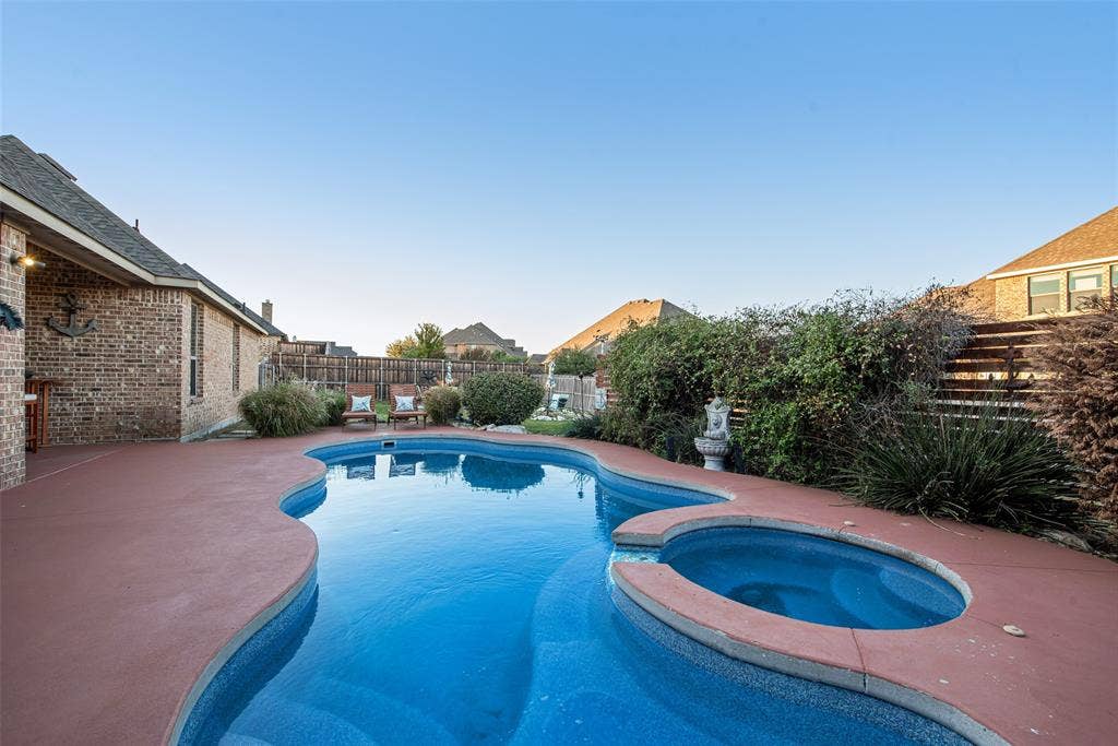 7231 Judy Drive, Ovilla, TX 75154 Freeform swimming pool with integrated spa, masonry brick exterior, and covered patio area