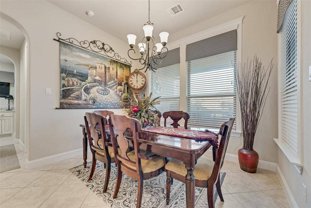7231 Judy Drive, Ovilla, TX 75154 Dining area featuring large-format tile flooring, arched entryway, multi-light iron chandelier, and oversized windows with window treatments