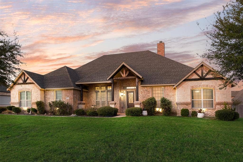7231 Judy Drive, Ovilla, TX 75154 Single-story brick exterior featuring a multi-gabled roofline, decorative timber gable accents, a brick chimney, and a covered front entryway
