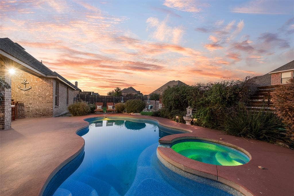 7231 Judy Drive, Ovilla, TX 75154 Curved swimming pool with an integrated spa, set within a stamped concrete patio and enclosed by a brick exterior wall