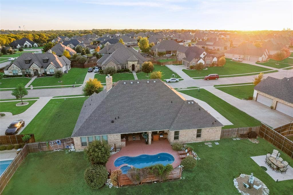 7231 Judy Drive, Ovilla, TX 75154 Aerial view of brick exterior residence featuring a covered patio, swimming pool with integrated spa, manicured lawn, and wood privacy fencing
