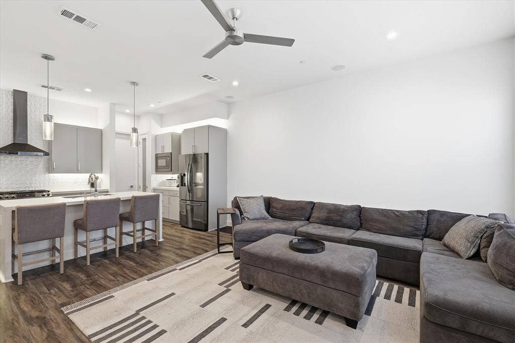 1813 Park Avenue, #106, Dallas, TX 75215 Kitchen featuring a quartz-topped island, stainless steel appliances, flat-panel cabinetry, a stainless steel range hood, and wood-finish flooring