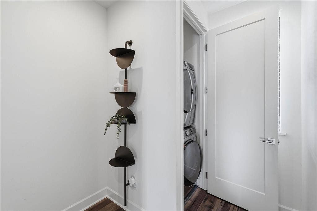 1813 Park Avenue, #106, Dallas, TX 75215 Dedicated laundry area featuring a stacked washer and dryer, wood-finish flooring, and a solid-core interior door with modern lever hardware