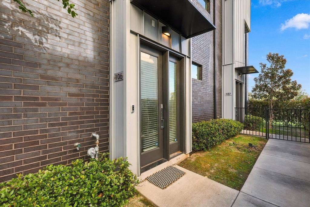 1813 Park Avenue, #106, Dallas, TX 75215 Contemporary exterior featuring dark brick masonry, vertical metal panel siding, a metal door awning, and a glass-paneled entry door