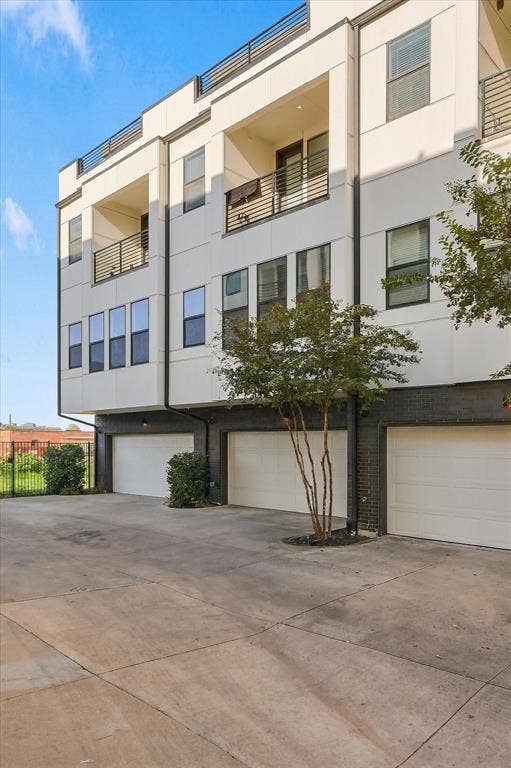 1813 Park Avenue, #106, Dallas, TX 75215 Modern multi-story exterior featuring a white panel facade, dark brick lower level, private balconies with metal railings, and three individual garage bays