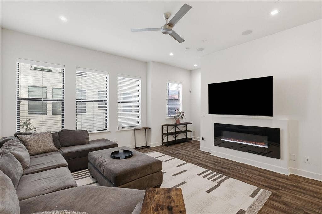 1813 Park Avenue, #106, Dallas, TX 75215 Living area featuring wood-finish flooring, a wall-mounted electric fireplace, recessed lighting, a modern ceiling fan, and large windows with horizontal blinds