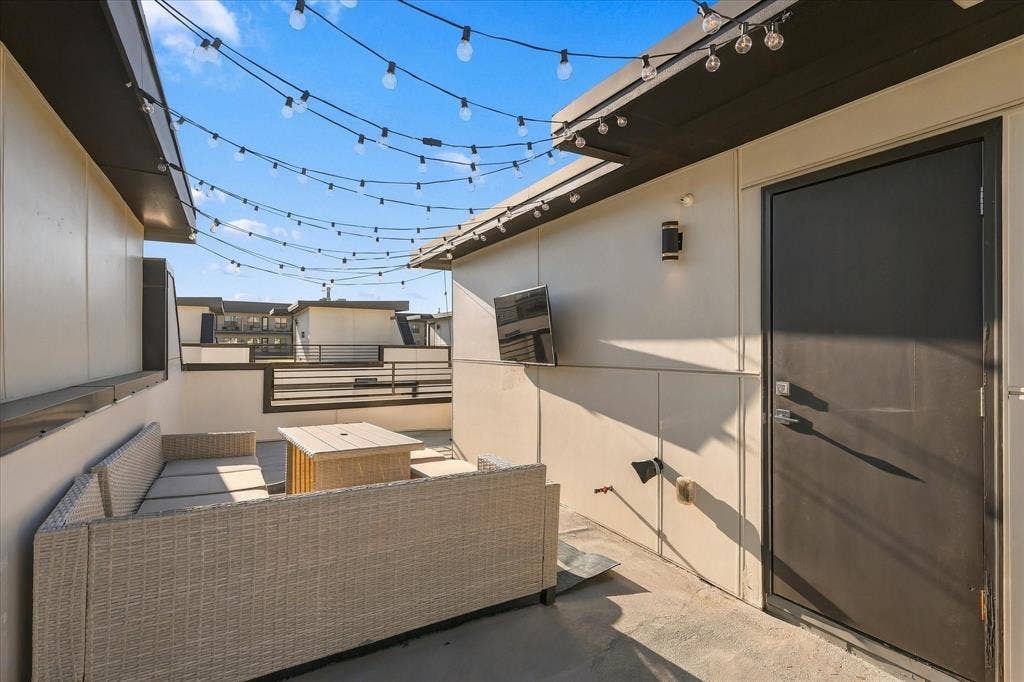 1813 Park Avenue, #106, Dallas, TX 75215 Rooftop terrace featuring concrete flooring, overhead string lighting, a wall-mounted television, and metal railing