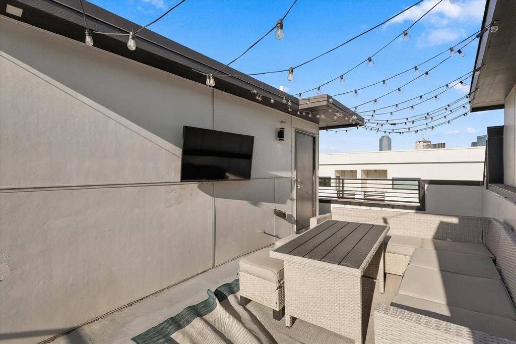 1813 Park Avenue, #106, Dallas, TX 75215 Rooftop terrace featuring smooth stucco walls, metal railing, and overhead string lighting