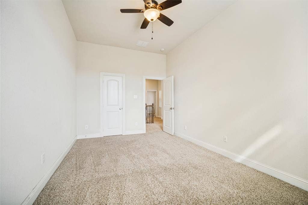 High ceilings featuring a central ceiling fan with integrated lighting and neutral carpeting