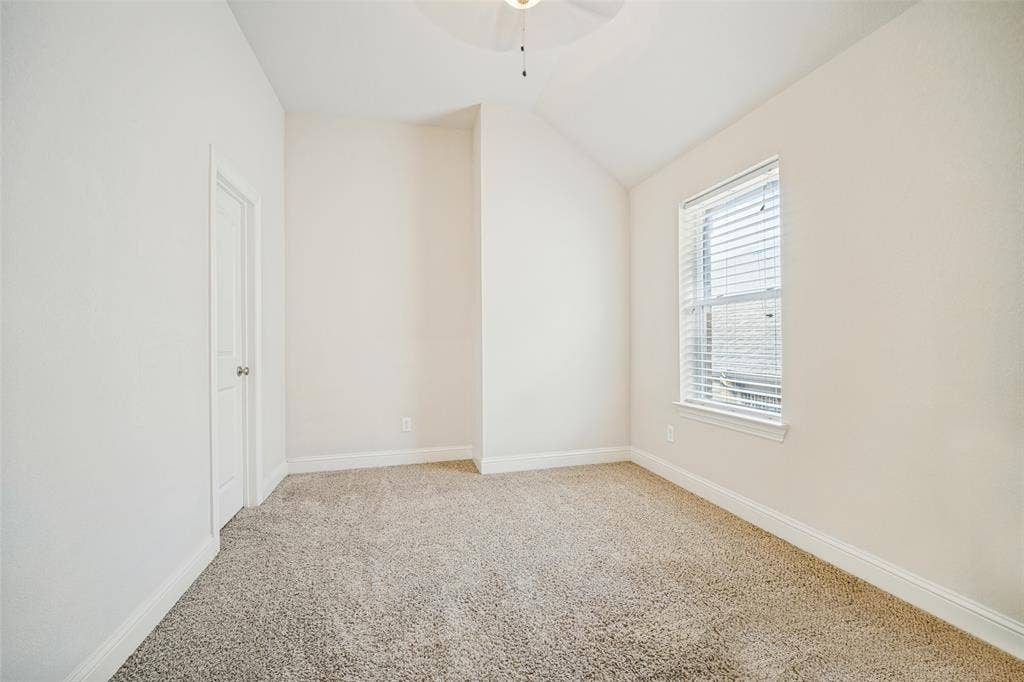 Interior space featuring vaulted ceilings, neutral wall tones, textured carpeting, and a window with horizontal blinds