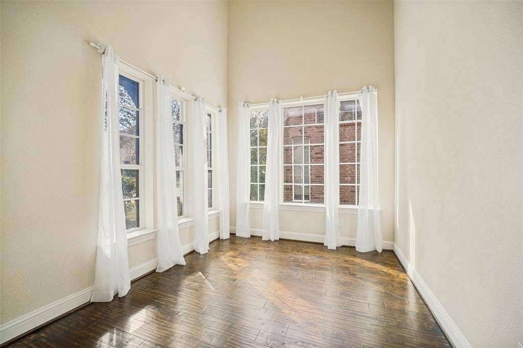 High-ceilinged room featuring wood-finish flooring and expansive windows with multi-pane grid detailing