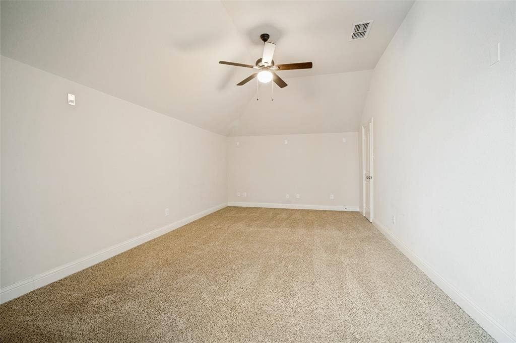 Vaulted ceilings, neutral carpeting, and a ceiling fan with integrated lighting