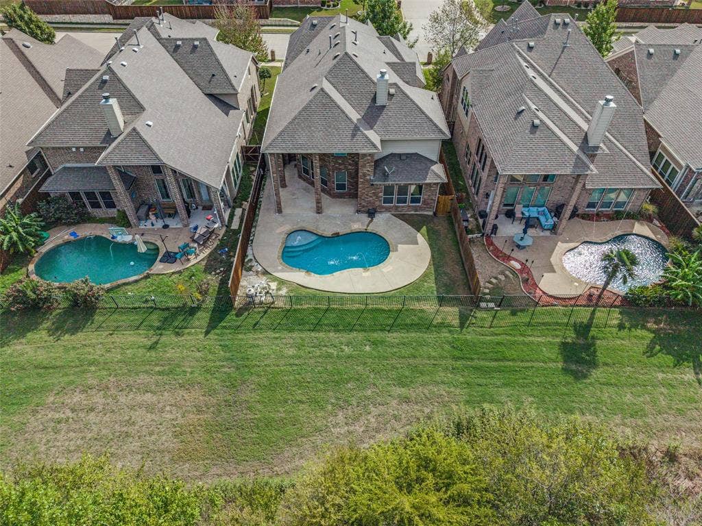 Multi-story residence featuring a brick and stone exterior, a covered back patio, an in-ground swimming pool, and an expansive greenbelt