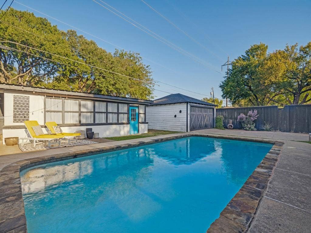 200 S Weatherred Drive, Richardson, TX 75080 In-ground swimming pool with stone coping, concrete patio, detached garage, and wood privacy fencing