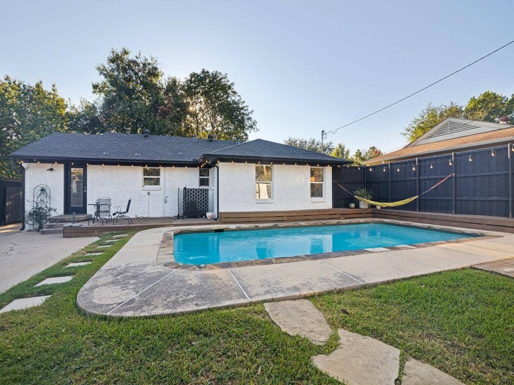 200 S Weatherred Drive, Richardson, TX 75080 Backyard oasis featuring an in-ground pool, concrete decking, wood-plank perimeter fencing, and flagstone stepping stones set in the lawn