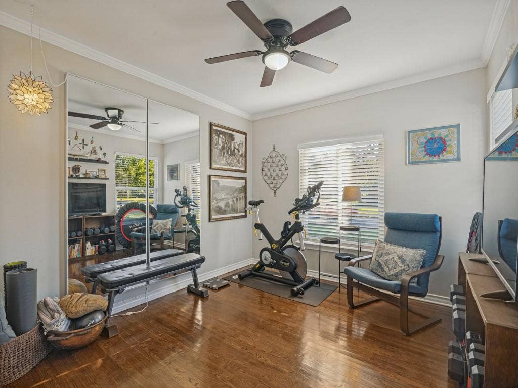 200 S Weatherred Drive, Richardson, TX 75080 Room featuring wood-finish flooring, full-wall mirrored paneling, a ceiling fan with integrated lighting, crown molding, and horizontal slat window blinds
