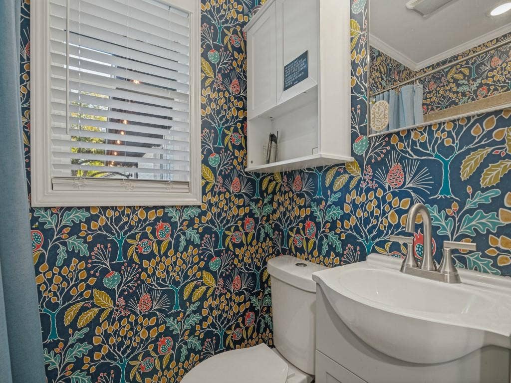 200 S Weatherred Drive, Richardson, TX 75080 Bathroom featuring white cabinetry, integrated sink, metal faucet, framed window with blinds, and built-in wall storage