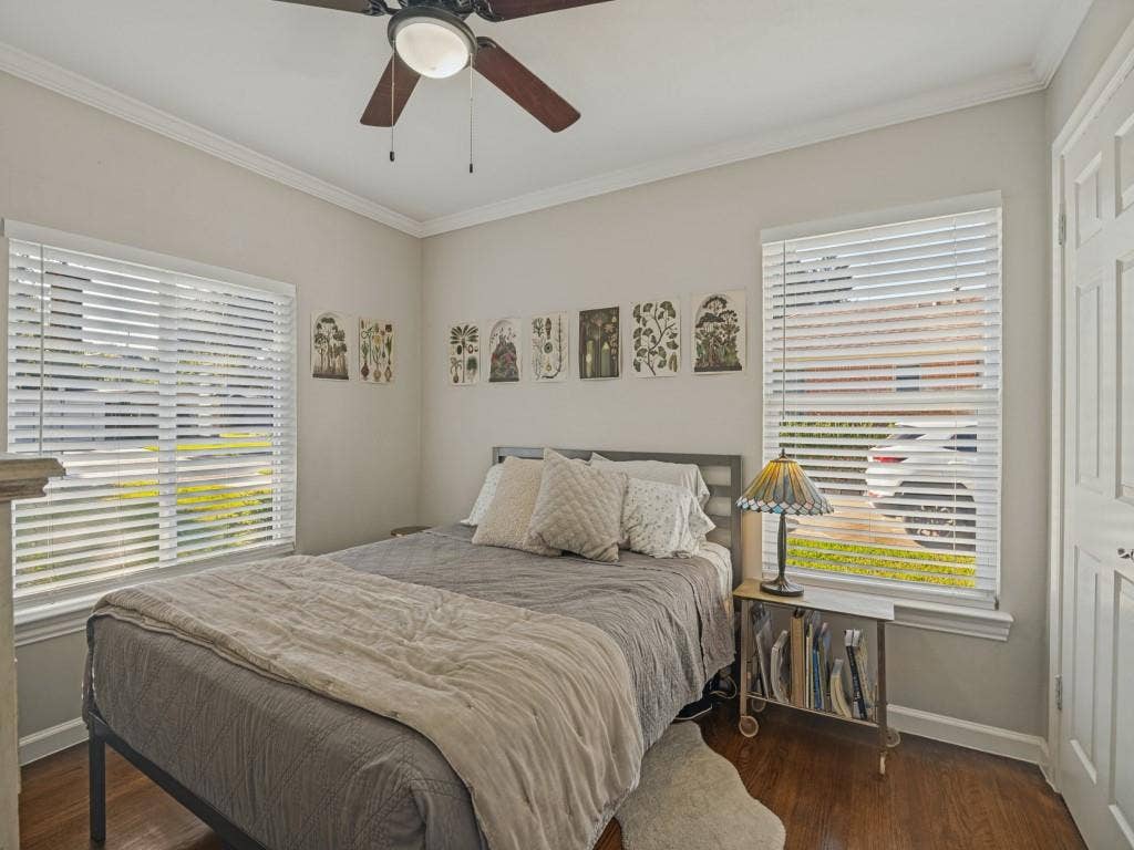 200 S Weatherred Drive, Richardson, TX 75080 Neutral-toned walls, wood-finish flooring, crown molding, dual windows with horizontal blinds, and a ceiling fan with integrated light fixture