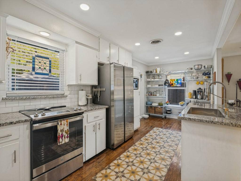 200 S Weatherred Drive, Richardson, TX 75080 Kitchen featuring white cabinetry, stone countertops, subway tile backsplash, stainless steel appliances, and wood-finish flooring