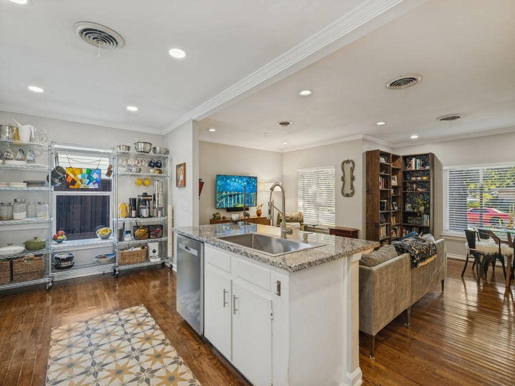 200 S Weatherred Drive, Richardson, TX 75080 Kitchen island featuring a stone-look countertop, stainless steel undermount sink, and white cabinetry, complemented by wood-finish flooring and recessed lighting