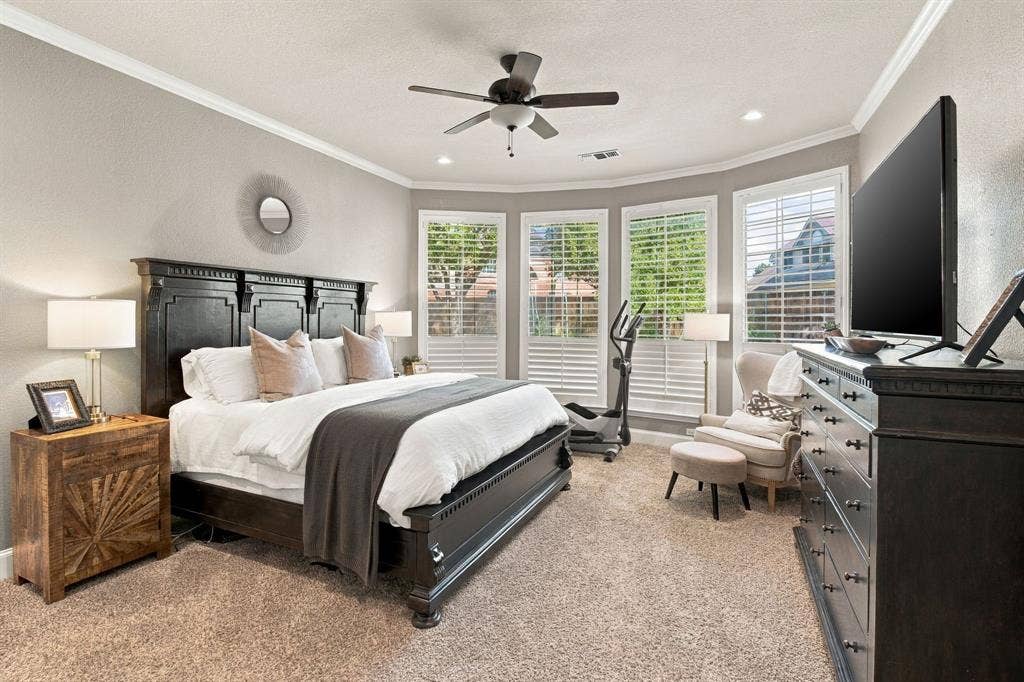 Neutral wall tones featuring crown molding, carpeting, recessed lighting, a ceiling fan, and bay windows equipped with white plantation shutters