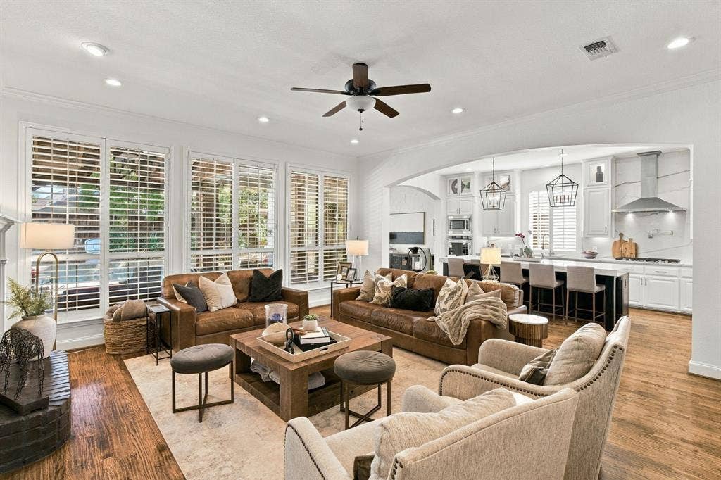 Open floor plan featuring wood-finish flooring, recessed lighting, white cabinetry, arched architectural detailing, and plantation shutters