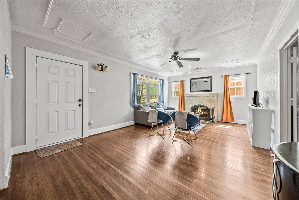 2807 Cain Boulevard, Dallas, TX 75211 Wood-finish flooring throughout, a ceiling fan, a stone-faced fireplace, crown molding, and multiple windows