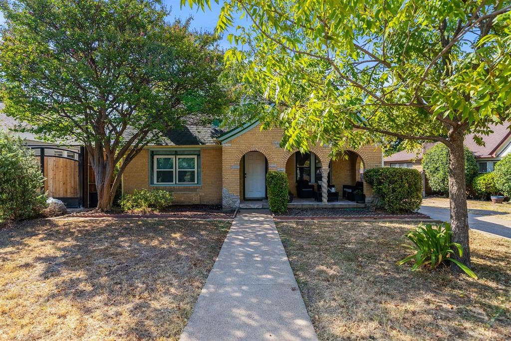 2807 Cain Boulevard, Dallas, TX 75211 Brick exterior with arched entryway, covered front porch, and mature trees