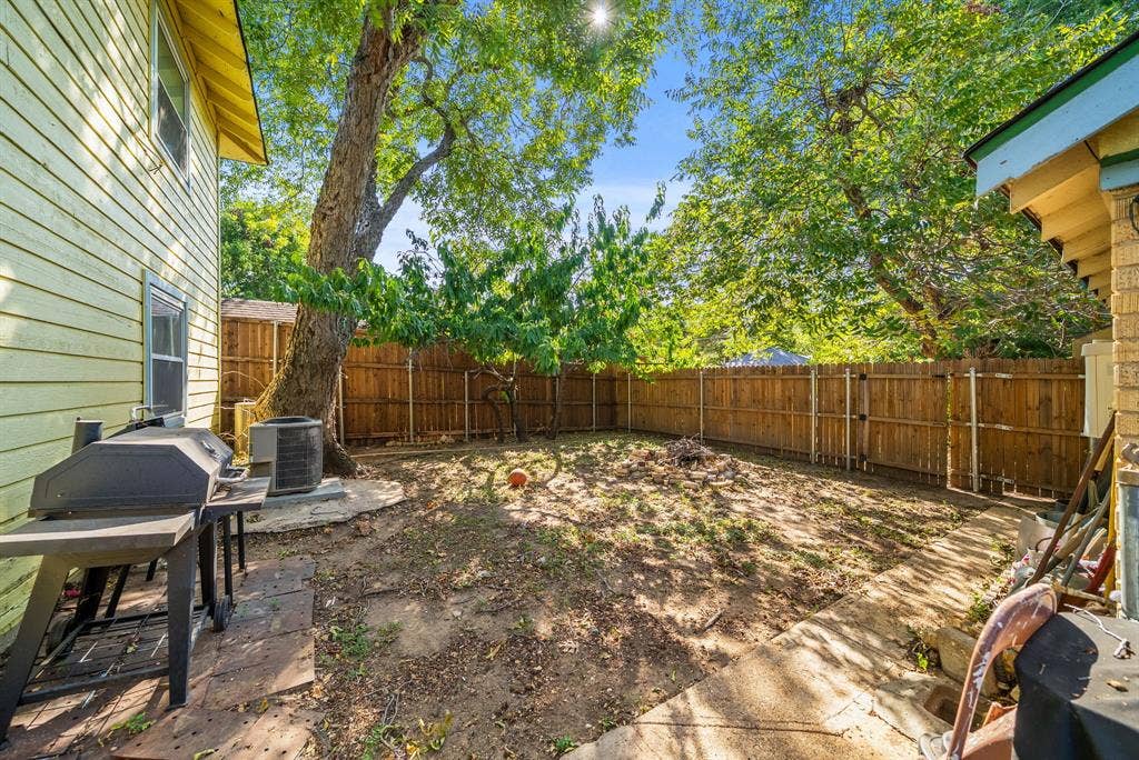 2807 Cain Boulevard, Dallas, TX 75211 Expansive backyard featuring a wood fence, mature trees, and a concrete patio