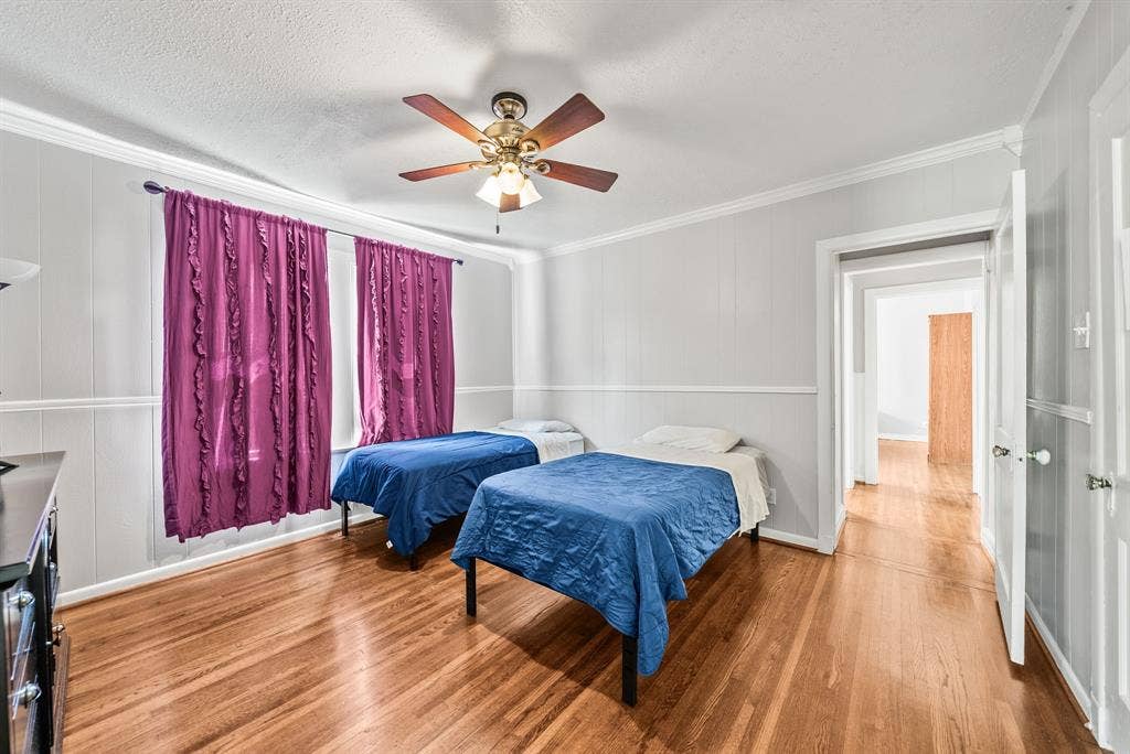 2807 Cain Boulevard, Dallas, TX 75211 Hardwood flooring with a warm finish, wall paneling, crown molding, and a ceiling fan with integrated lighting