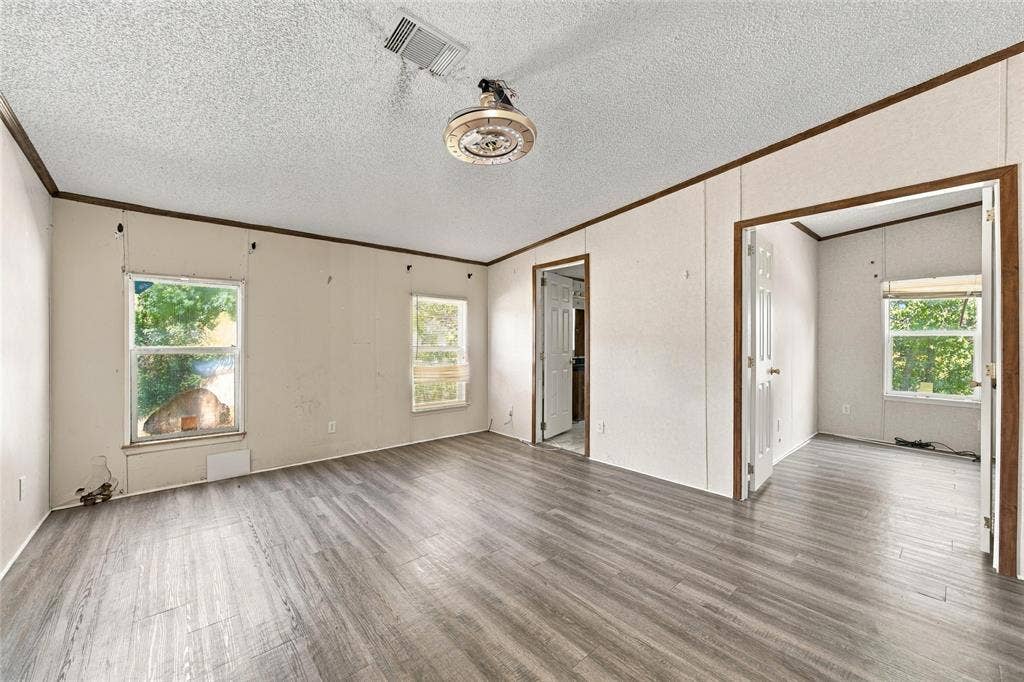 Interior space featuring wood-finish flooring, textured ceiling, two windows, and an attached overhead light fixture