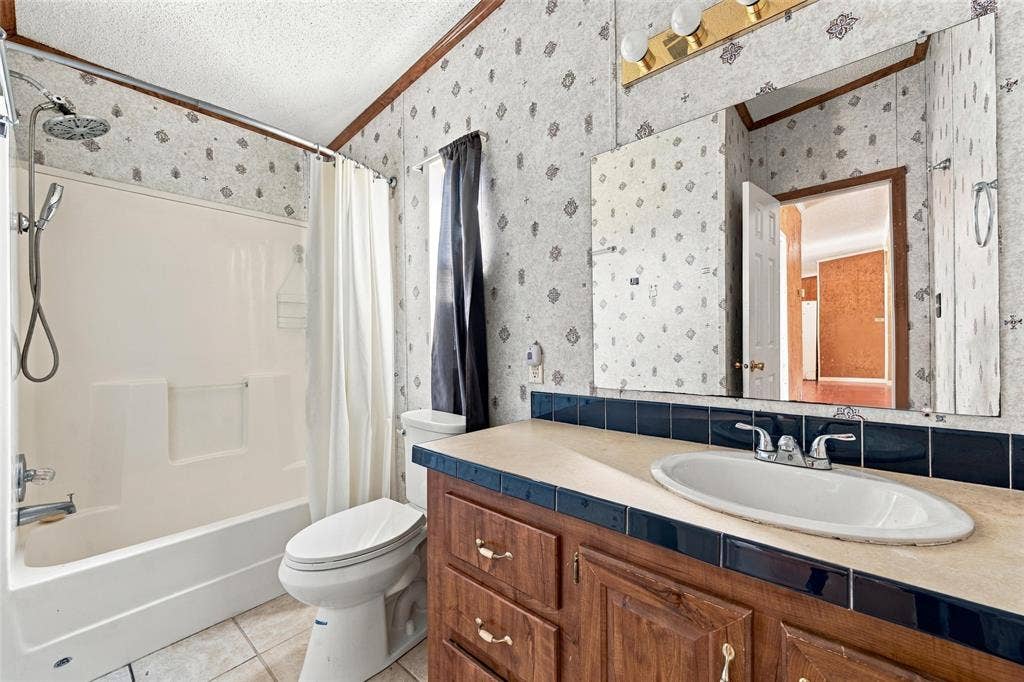 Bathroom featuring a tub-shower combination with a surround, wood-finish vanity cabinetry, a solid-surface countertop with an integrated basin, and a wall-mounted mirror with integrated lighting