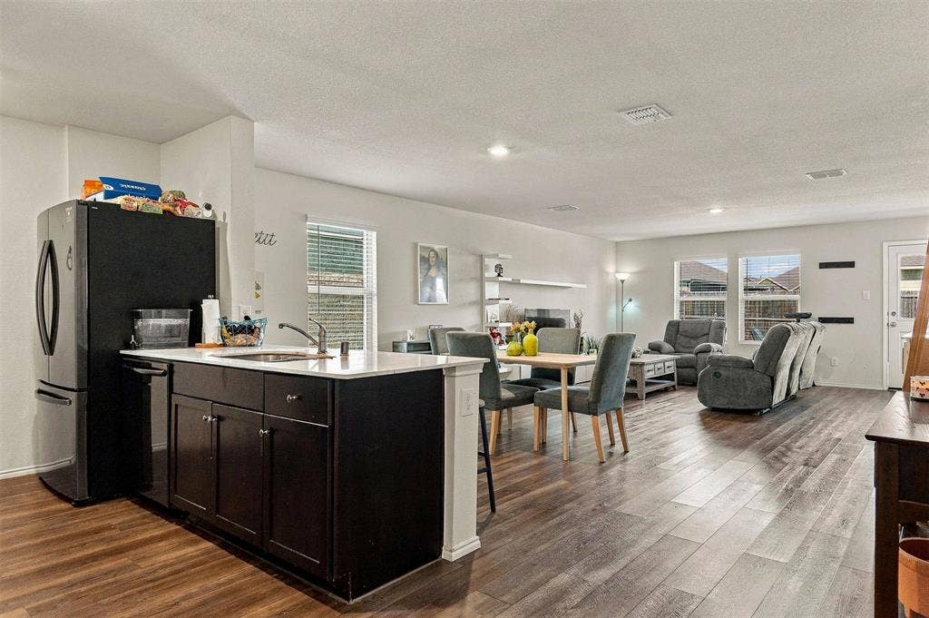 1516 Stonefield Drive, Anna, TX 75409 Spacious living area with wood-look flooring and an open layout connecting the dining area and kitchen.