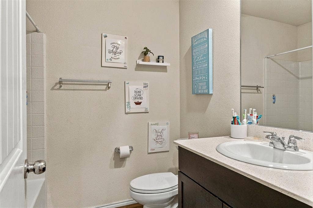 1516 Stonefield Drive, Anna, TX 75409 Bathroom featuring a dark-finish vanity, solid-surface countertop with an integrated oval sink, chrome-finish faucet, and a large wall-mounted mirror