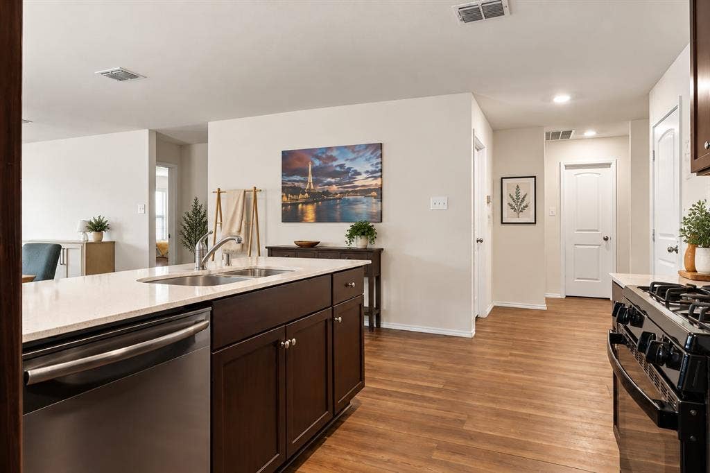 1516 Stonefield Drive, Anna, TX 75409 Kitchen featuring a stone-surface countertop, dark wood cabinetry, stainless steel dishwasher, gas range, and wood-finish flooring