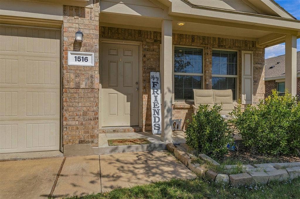 1516 Stonefield Drive, Anna, TX 75409 Brick façade exterior featuring a covered front porch, stone-bordered landscaping, and a multi-panel garage door