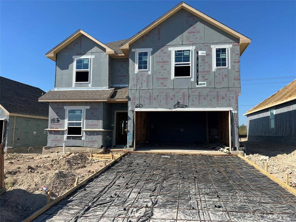 11813 Ceres Street, Lorena, TX 76655 Two-story residential structure featuring a gable roof, multiple sash windows, and an attached two-car garage with a prepared concrete foundation