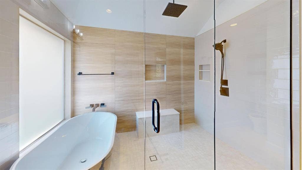 2254 Ash Grove Way, Dallas, TX 75228 Freestanding soaking tub with wall-mounted fixtures, frameless glass shower enclosure, wood-finish tile wall surround, built-in tiled shower bench, and recessed wall niche