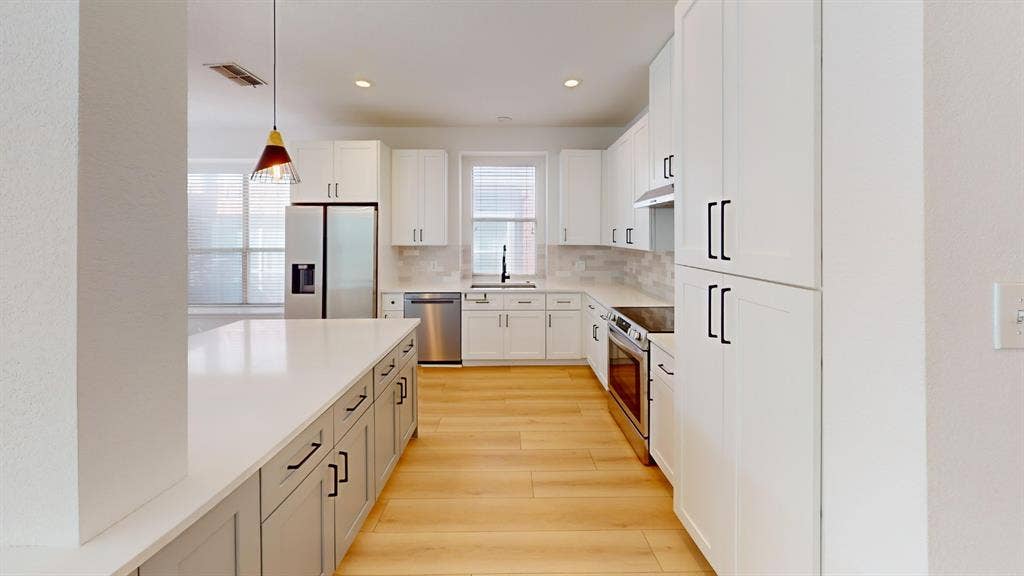 2254 Ash Grove Way, Dallas, TX 75228 Kitchen featuring white shaker-style cabinetry, a quartz-topped central island, stainless steel appliances, light-toned wood-finish flooring, and recessed lighting