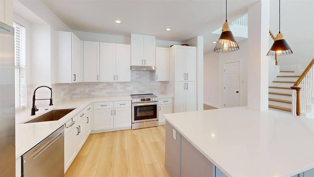 2254 Ash Grove Way, Dallas, TX 75228 Kitchen featuring white shaker-style cabinetry, solid-surface countertops, subway tile backsplash, stainless steel appliances, and wood-finish flooring