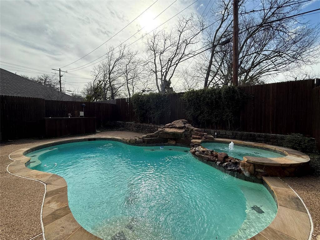 2254 Ash Grove Way, Dallas, TX 75228 Freeform swimming pool with a stone rock feature, integrated spa, built-in water fountain, and surrounding stone coping