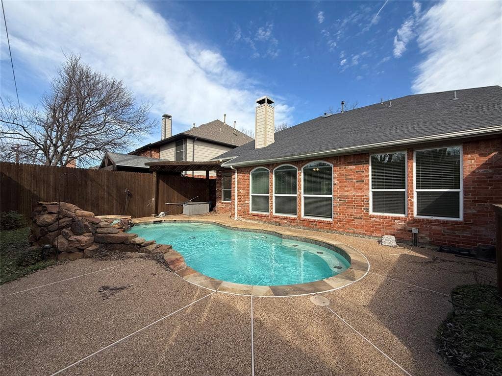 2254 Ash Grove Way, Dallas, TX 75228 Backyard featuring an in-ground swimming pool, stone water feature, aggregate concrete decking, and wood privacy fencing