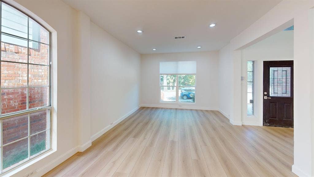 2254 Ash Grove Way, Dallas, TX 75228 Open interior space featuring light-tone wood-finish flooring, recessed lighting, expansive windows, and a dark-finish front door with decorative glass paneling