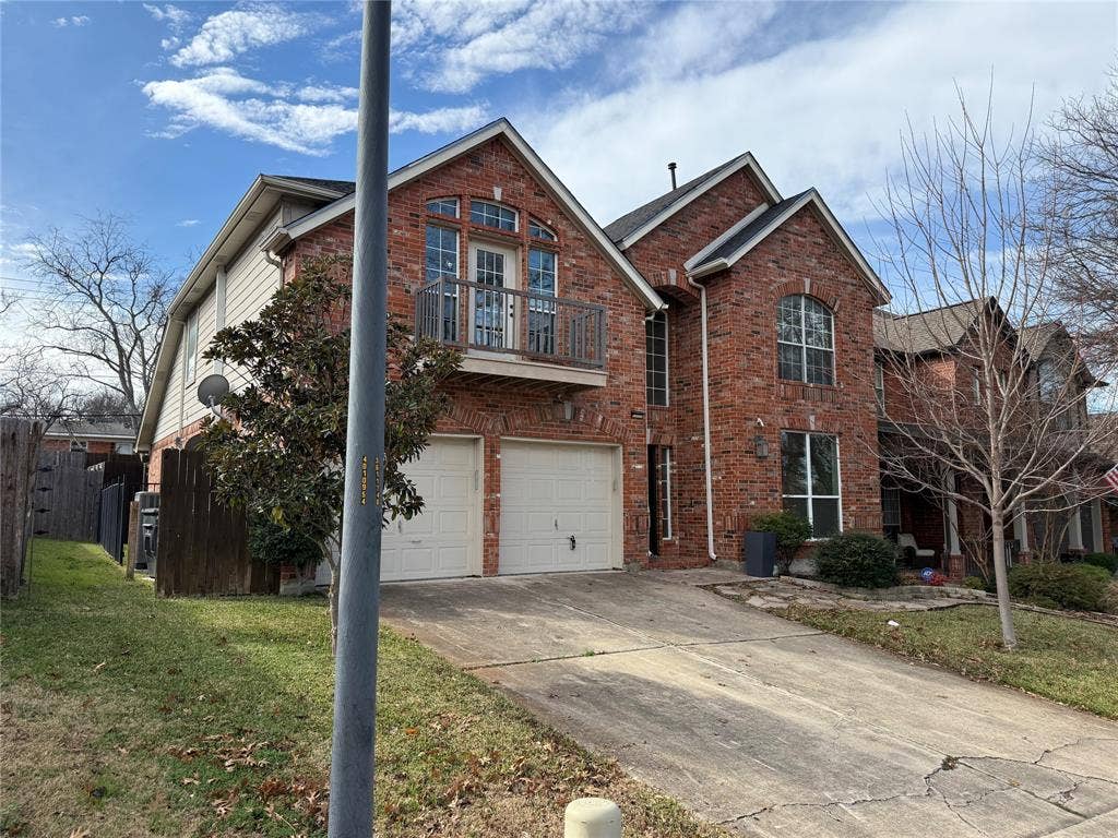 2254 Ash Grove Way, Dallas, TX 75228 Multi-story brick exterior featuring a balcony with metal railing, arched window accents, and a two-car garage