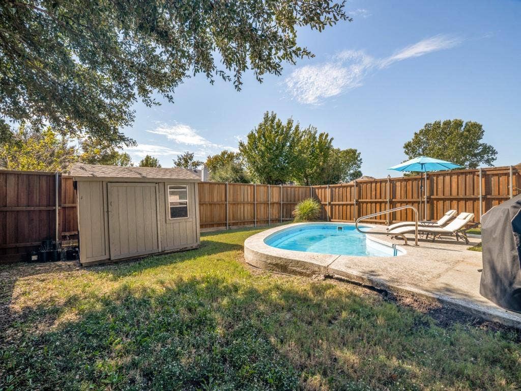 1728 Harvest Crossing Drive, Wylie, TX 75098 Backyard featuring an inground pool with concrete decking, a wooden perimeter fence, and a storage shed