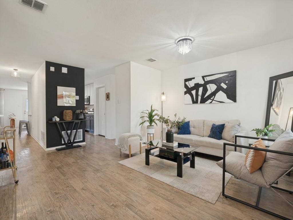 1728 Harvest Crossing Drive, Wylie, TX 75098 Living space featuring wood-finish flooring, a contemporary crystal flush-mount light fixture, and a distinct black accent wall