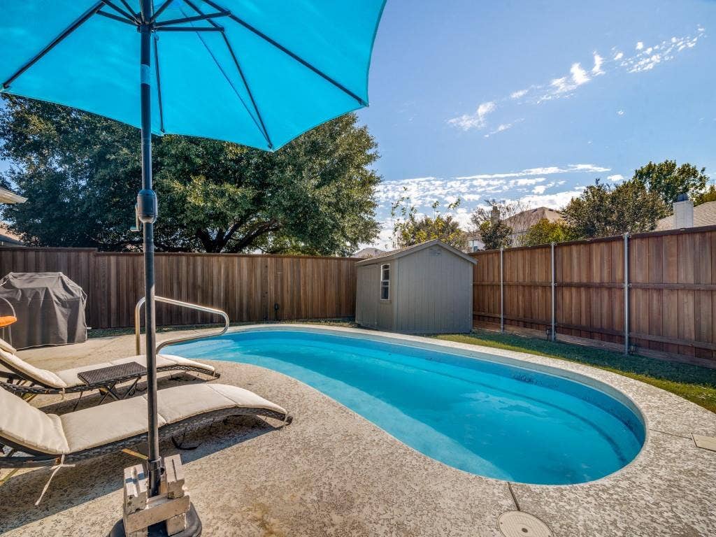1728 Harvest Crossing Drive, Wylie, TX 75098 Backyard featuring an inground pool with a textured concrete deck, enclosed by a wood privacy fence and including a storage shed