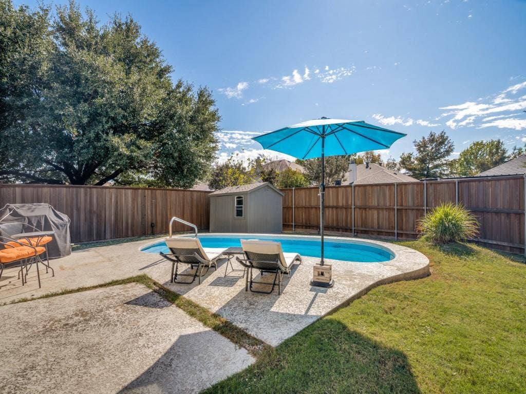 1728 Harvest Crossing Drive, Wylie, TX 75098 Backyard featuring an in-ground swimming pool, concrete decking, wood privacy fencing, and a detached storage structure
